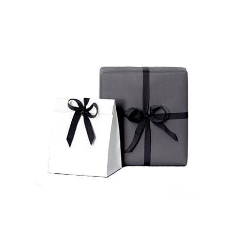 Minimalistisch verpackte Geschenke in Weiß und Dunkelgrau mit schwarzen Schleifen vor weißem Hintergrund